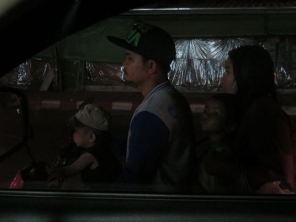 Automme ikkunan takana tyypillinen perhekuljetus: mopon selässä isä, äiti ja kaksi pikkulasta